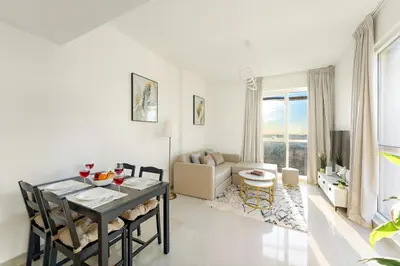 a white living room with a table and a couch at Luxury 1BR with Lake View Near Downtown Balcony and Pool Access in Dubai