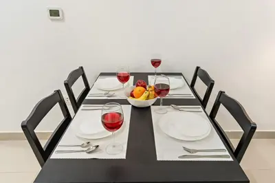 a table with glasses of wine and a bowl of fruit at Luxury 1BR with Lake View Near Downtown Balcony and Pool Access in Dubai