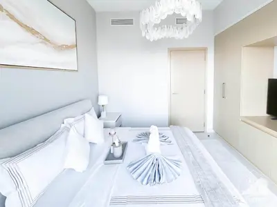 a white bedroom with a bed and a chandelier at Luxurious Burj Royale 1B Apt With Balcony & City Views in Dubai