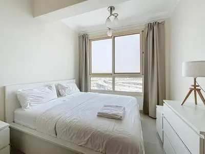a white bedroom with a bed and a window at Marina 1 Bedroom Gem in Dubai