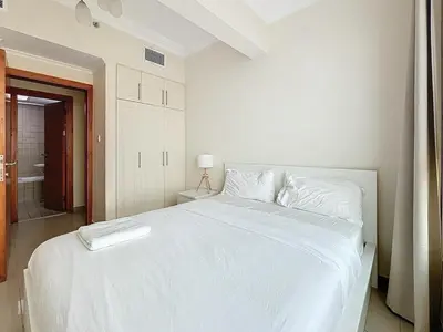 a white bed in a white bedroom with a bathroom at Marina 1 Bedroom Gem in Dubai