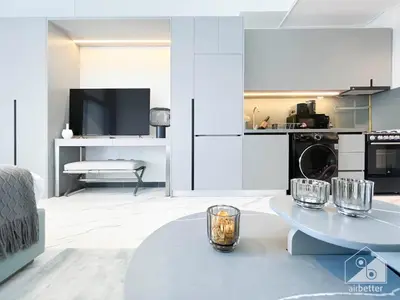 a white living room with a table and a tv at Stylish Studio Getaway in Dubai's MAG 920 in Dubai