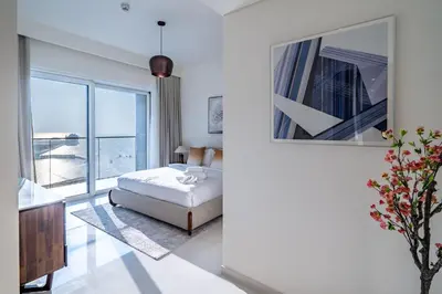 a bedroom with a bed and a large window at Homes Beyond I Stunning Oceanfront 2 BR Apartment in Dubai