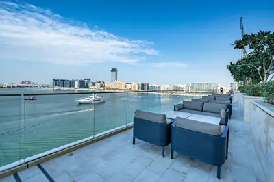 a balcony with chairs and a view of the water at Homes Beyond I Stunning Oceanfront 2 BR Apartment in Dubai
