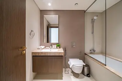 a bathroom with a sink and a toilet and a mirror at Homes Beyond I Stunning Oceanfront 2 BR Apartment in Dubai