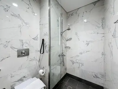 a white bathroom with a shower and a toilet at Family friendly 2-bedroom in Dubai