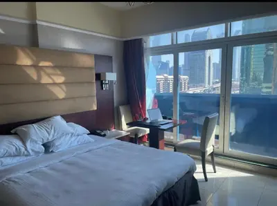 a hotel room with a bed and a desk and a window at Cozy Dubai Marina Suite in Dubai