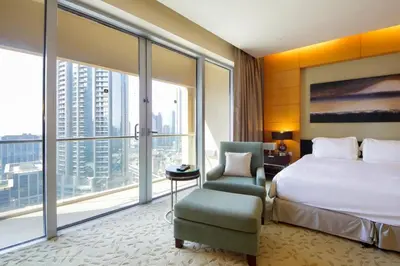 a bedroom with a bed and a chair and a large window at Partial Burjkhalifa View from Balcony in Dubai Mall-Studio King Bed in Dubai