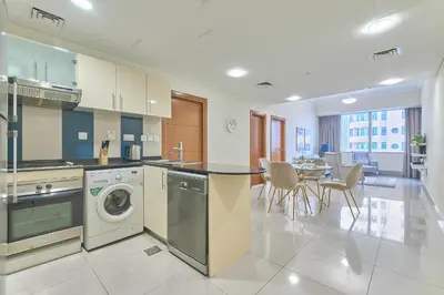 a kitchen with a washing machine and a table with chairs at Cozy 2bd in Dubai Marina in Dubai