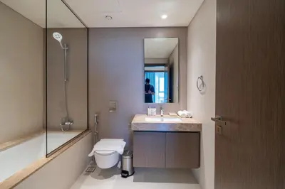 a bathroom with a toilet and a sink and a mirror at Homes Beyond I Modern 2BR Getaway with Beach Access in Dubai