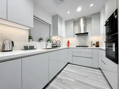 a white kitchen with white cabinets and appliances at Souk Al Bahar Dubai Fountain and Burj Khalifa view from the Balcony, 2 mins walk to Dubai Mall by Norbu Holiday Homes in Dubai