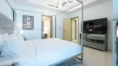 a bedroom with a large white bed and a flat screen tv at KeyRock Living - Luxe Retreat at Paramount in Dubai
