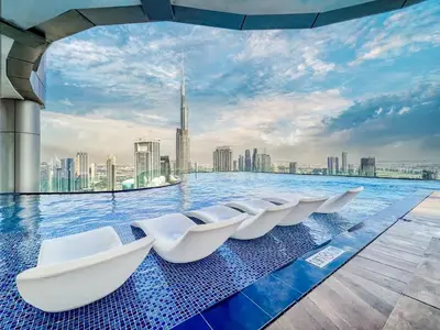 a row of white chairs in a pool with a city skyline at 5 Star Stay, Infinity Pool with Burj Khalifa Views in Dubai