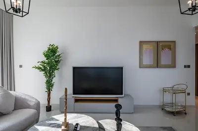 a living room with a flat screen tv on a white wall at Homes Beyond l Relaxing 1BR Oasis with Beach Access in Dubai