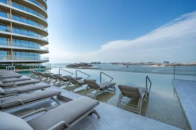 a row of chaise lounge chairs on a balcony with the ocean at Homes Beyond l Relaxing 1BR Oasis with Beach Access in Dubai
