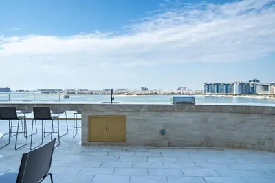 a patio with chairs and a bar with a view at Homes Beyond l Relaxing 1BR Oasis with Beach Access in Dubai