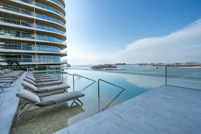 a row of lounge chairs on a balcony overlooking the water at Homes Beyond l Relaxing 1BR Oasis with Beach Access in Dubai