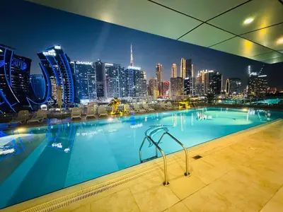 a large swimming pool with a city skyline at night at Premium Large Studio in Hamilton residency business bay Marasi Drive Dubai in Dubai