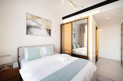 a bedroom with a large bed and a mirror at Brand New Apt On Top Floor 1BR w Spa And Pool in Dubai