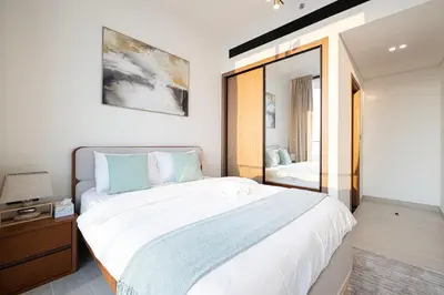 a bedroom with a large bed and a mirror at Brand New Apt On Top Floor 1BR w Spa And Pool in Dubai