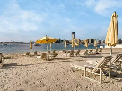 a group of chairs and umbrellas on a beach at Homes Beyond I Seaside 1BR Retreat with Beach Access in Dubai