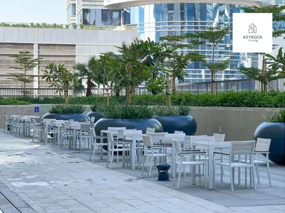 a row of white tables and chairs in front of a building at Exclusive Lakeview Haven - Zada Tower by Keyrock Living in Dubai