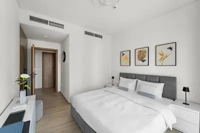 a white bedroom with a large bed and a desk at 1BR Palace Residences, City View in Dubai