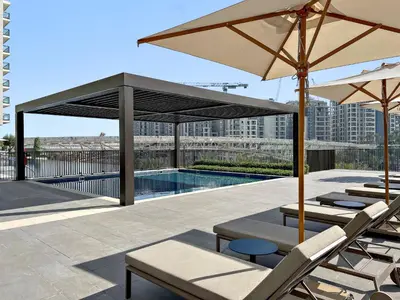 a patio with chairs and umbrellas and a pool at 1BR Palace Residences, City View in Dubai