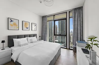 a white bedroom with a large bed and a window at 1BR Palace Residences, City View in Dubai