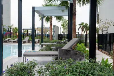 a patio with chairs and a swimming pool with palm trees at Keyrock Aykon Tower, Business Bay - Pool & Gym in Dubai