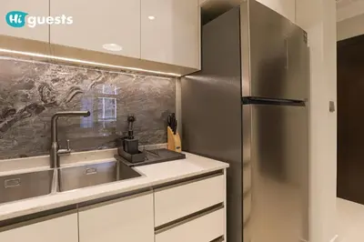 a kitchen with a sink and a stainless steel refrigerator at HiGuests - Stylish 1BR Retreat with Modern Interiors in Dubai in Dubai