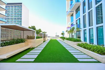 a walkway with green grass in a building at Pure Voyage JVC in Dubai