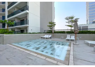 a swimming pool with two chairs and an umbrella and a building at Keyrock Living - Elegant City Escape at Zada Tower in Dubai
