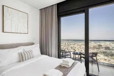 a bedroom with a white bed and a large window at UrbanStays Dubai - Paramount Midtown in Dubai