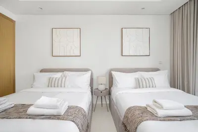 two beds in a white room with towels on them at UrbanStays Dubai - Paramount Midtown in Dubai