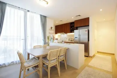 a kitchen with a table and chairs and a refrigerator at 015 - Le Pont 1 in Dubai
