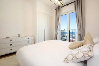 a white bedroom with a bed and a window at 015 - Le Pont 1 in Dubai