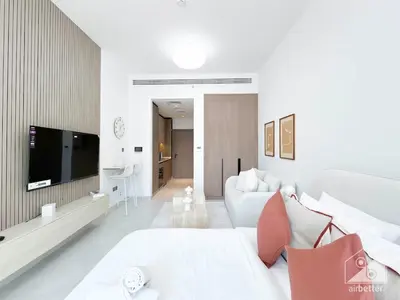a white living room with a white couch and a tv at Luxurious Studio in Arjan With Balcony & Views in Dubai