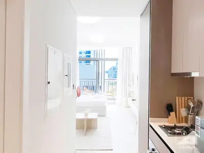 a kitchen with a white refrigerator and a living room at Luxurious Studio in Arjan With Balcony & Views in Dubai