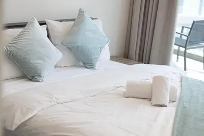 a white bed with pillows and a towel on it at NEW 2BR in Arjan with Private Pool in Dubai