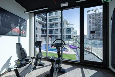 a gym with two cardio machines in a room with a large window at NEW 2BR in Arjan with Private Pool in Dubai