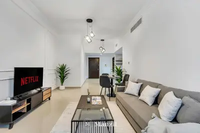 a living room with a couch and a tv at Luxury Studio Apartment in JVC near Circle Mall in Dubai