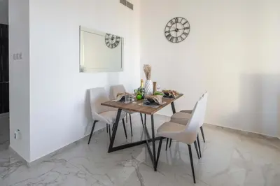 a dining room with a wooden table and white chairs at Frank Porter - Golden Dream Tower in Dubai