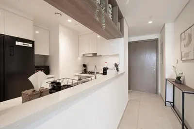 a kitchen with white cabinets and a black refrigerator at Beautiful 2BR - Burj Views And Dubai Mall Connection in Dubai
