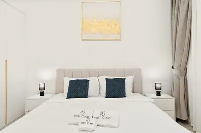 a white bedroom with a large bed with two night stands at Modern 1BR Apartment Steps from Beach and Dubai Nightlife in Dubai