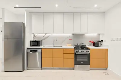 a kitchen with white cabinets and stainless steel appliances at Modern 1BR Apartment Steps from Beach and Dubai Nightlife in Dubai