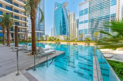 a swimming pool with palm trees and buildings at Keyrock - Zada Tower, Business Bay Lake-View Apartment in Dubai
