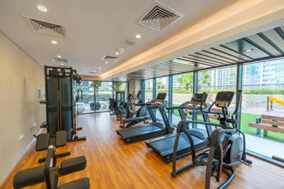 a gym with a row of treadmills and ellipticals at Keyrock - Zada Tower, Business Bay Lake-View Apartment in Dubai