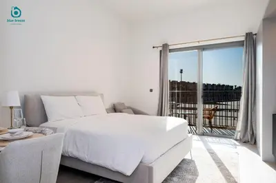 a white bedroom with a bed and a balcony at Blue Breeze - Stylish Studio Retreat in MBR City in Dubai
