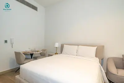 a bedroom with a bed and a chair and a table at Blue Breeze - Stylish Studio Retreat in MBR City in Dubai